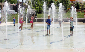 children play on a splash pad in the water fountains